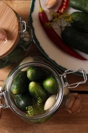 Photo of Jar with cucumbers, garlic and dill on wooden table, top view. Pickling recipe