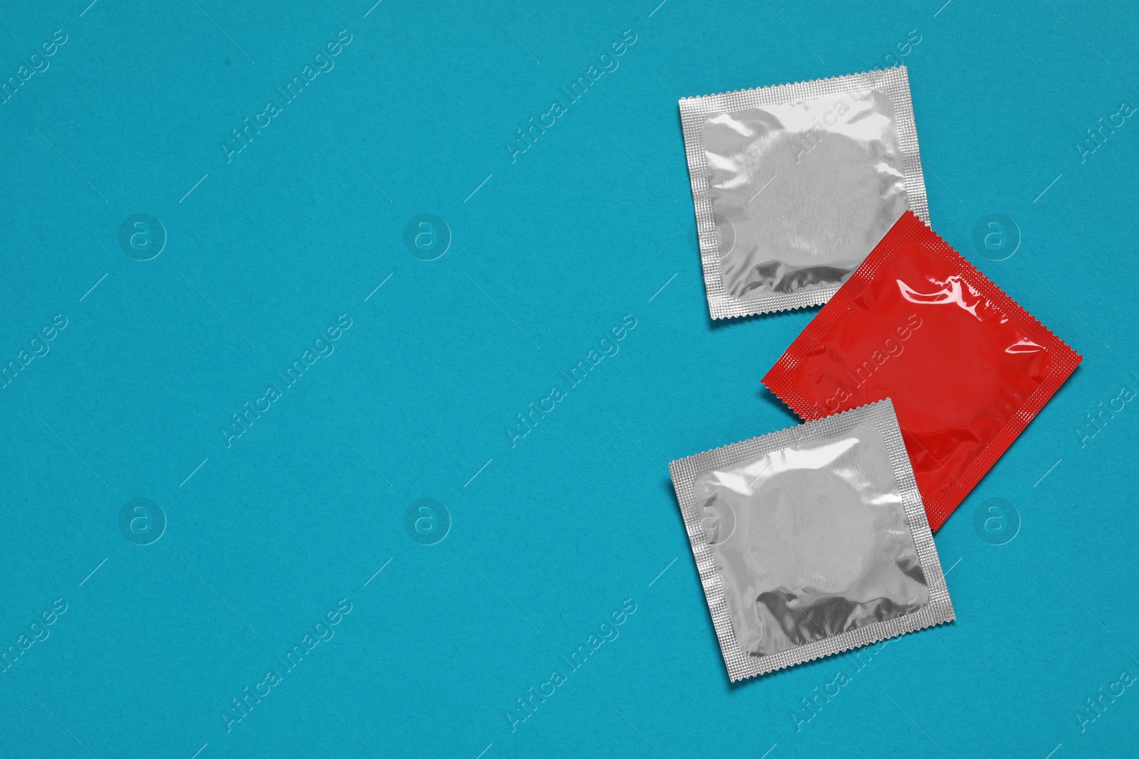 Photo of Condom packages on light blue background, flat lay and space for text. Safe sex