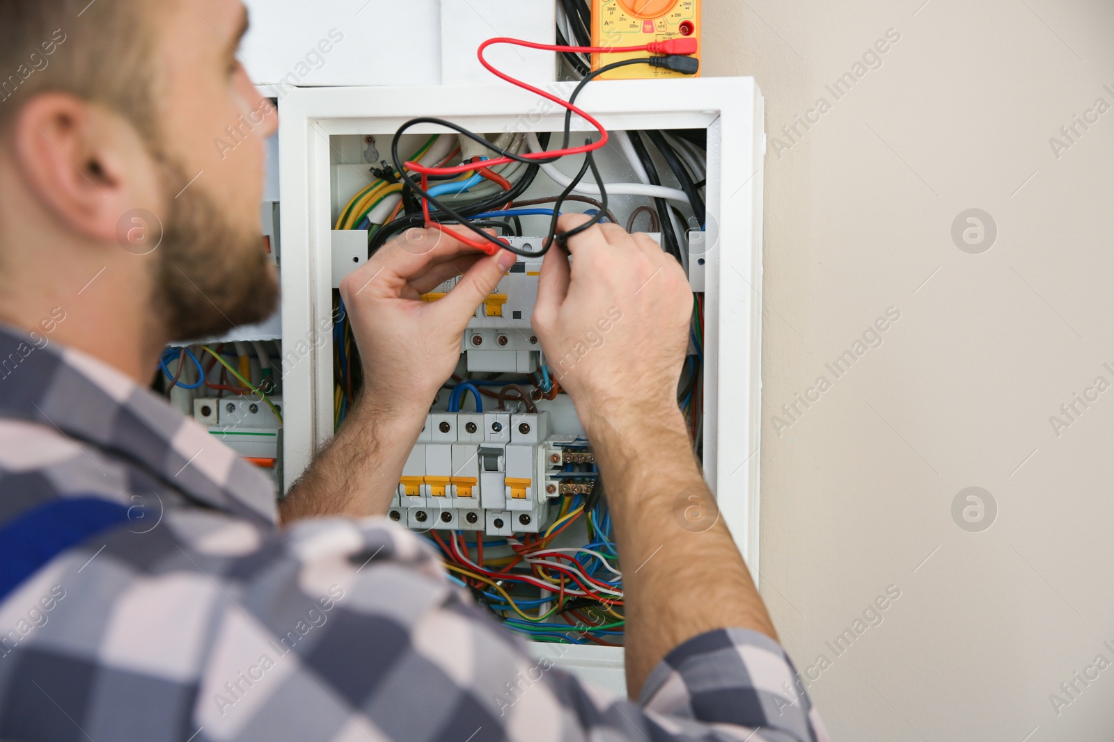 Photo of Electrician with tester checking voltage indoors, closeup