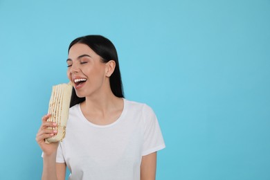 Photo of Young woman eating delicious shawarma on light blue background. Space for text