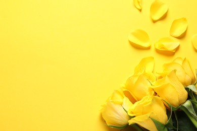 Beautiful fresh roses and petals on yellow background, flat lay. Space for text