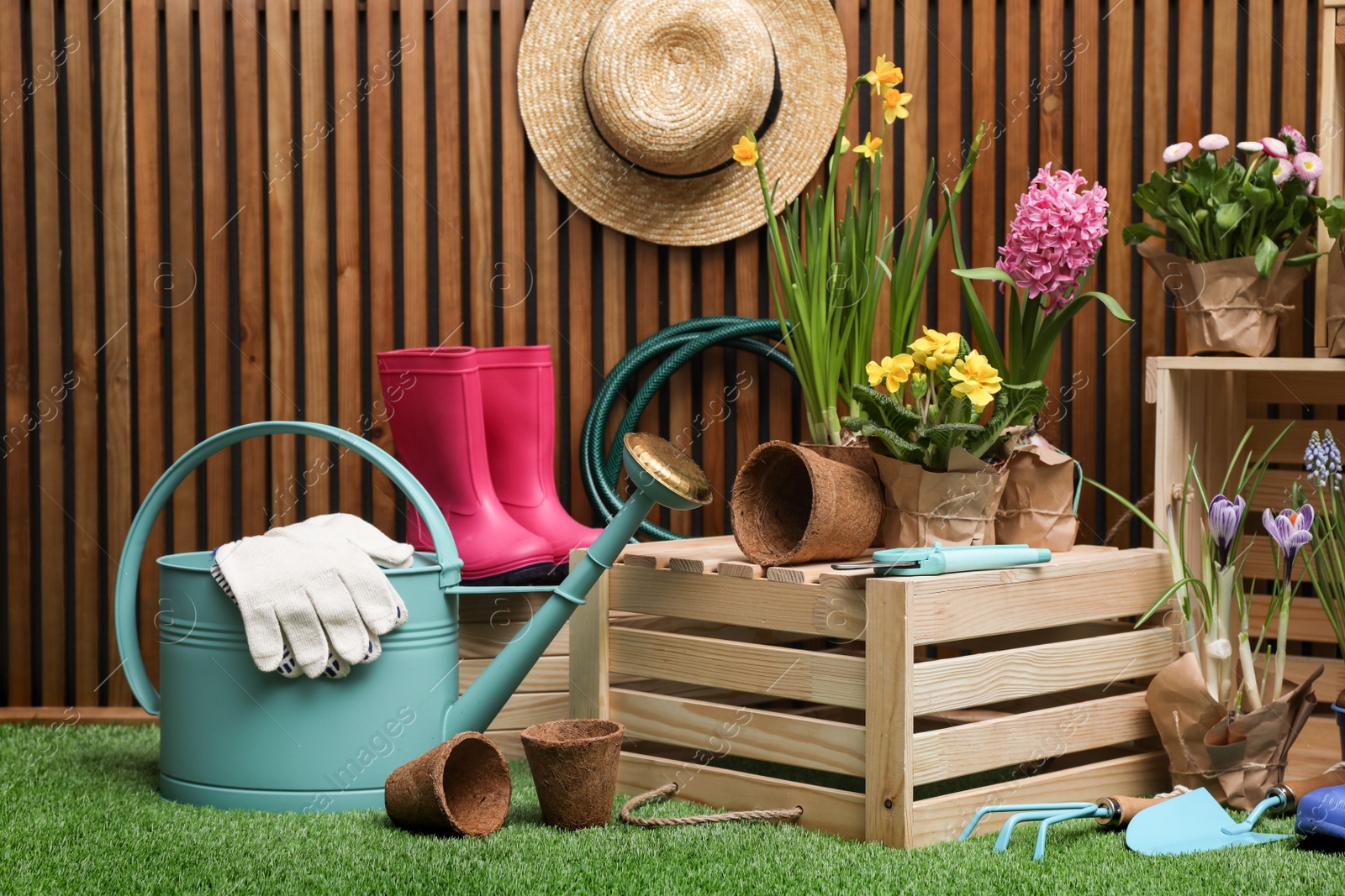 Photo of Composition with different gardening tools on artificial grass at wooden wall