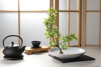 Stylish ikebana as house decor. Beautiful fresh branch and tea set on wooden table