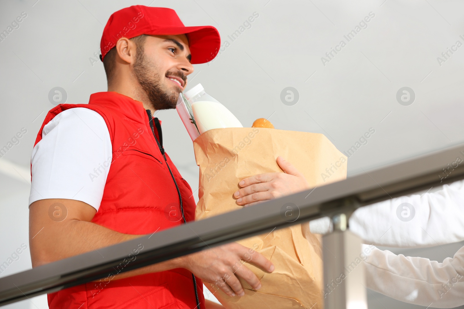Photo of Male courier delivering food to client indoors