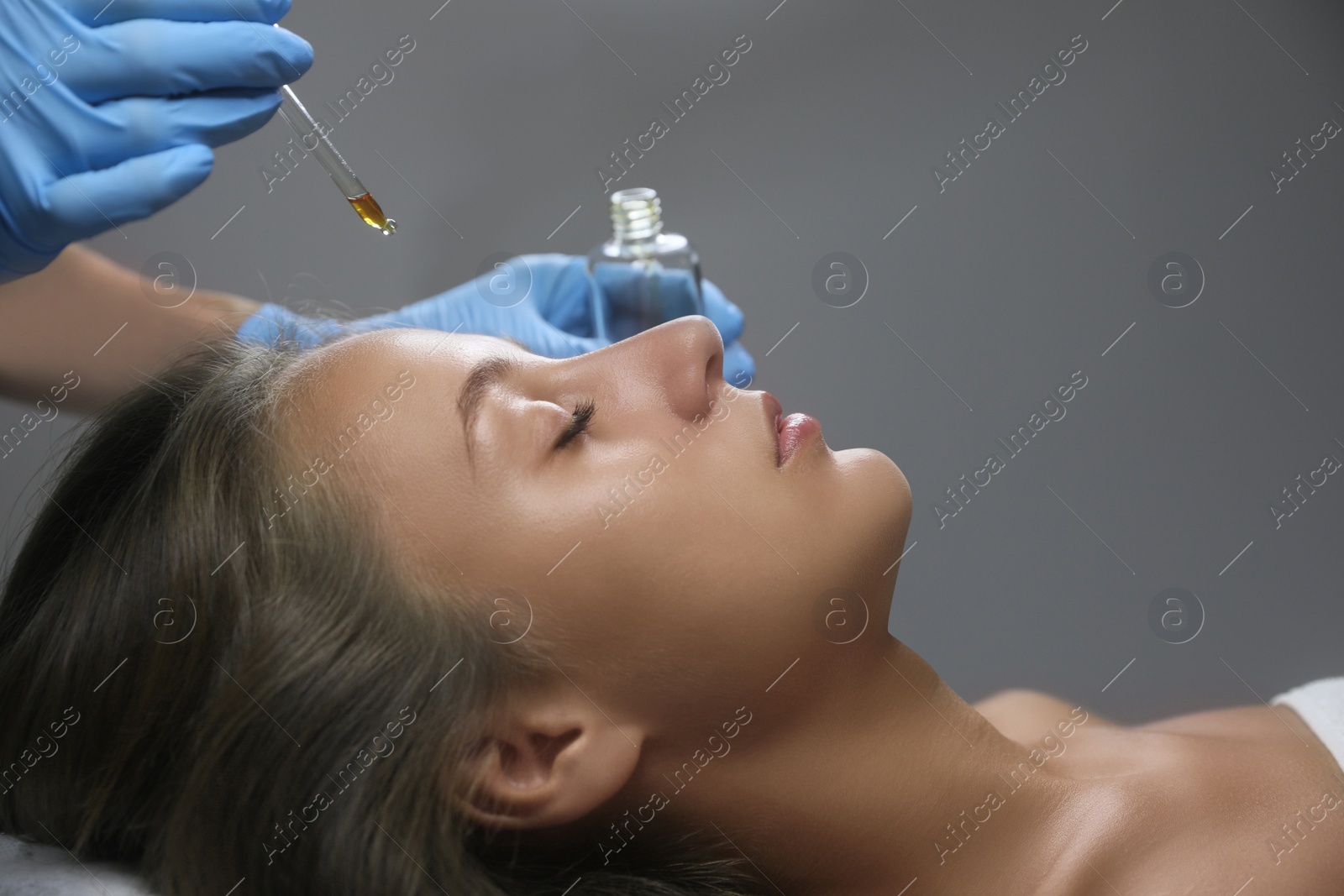 Photo of Cosmetologist applying serum on client's face in salon