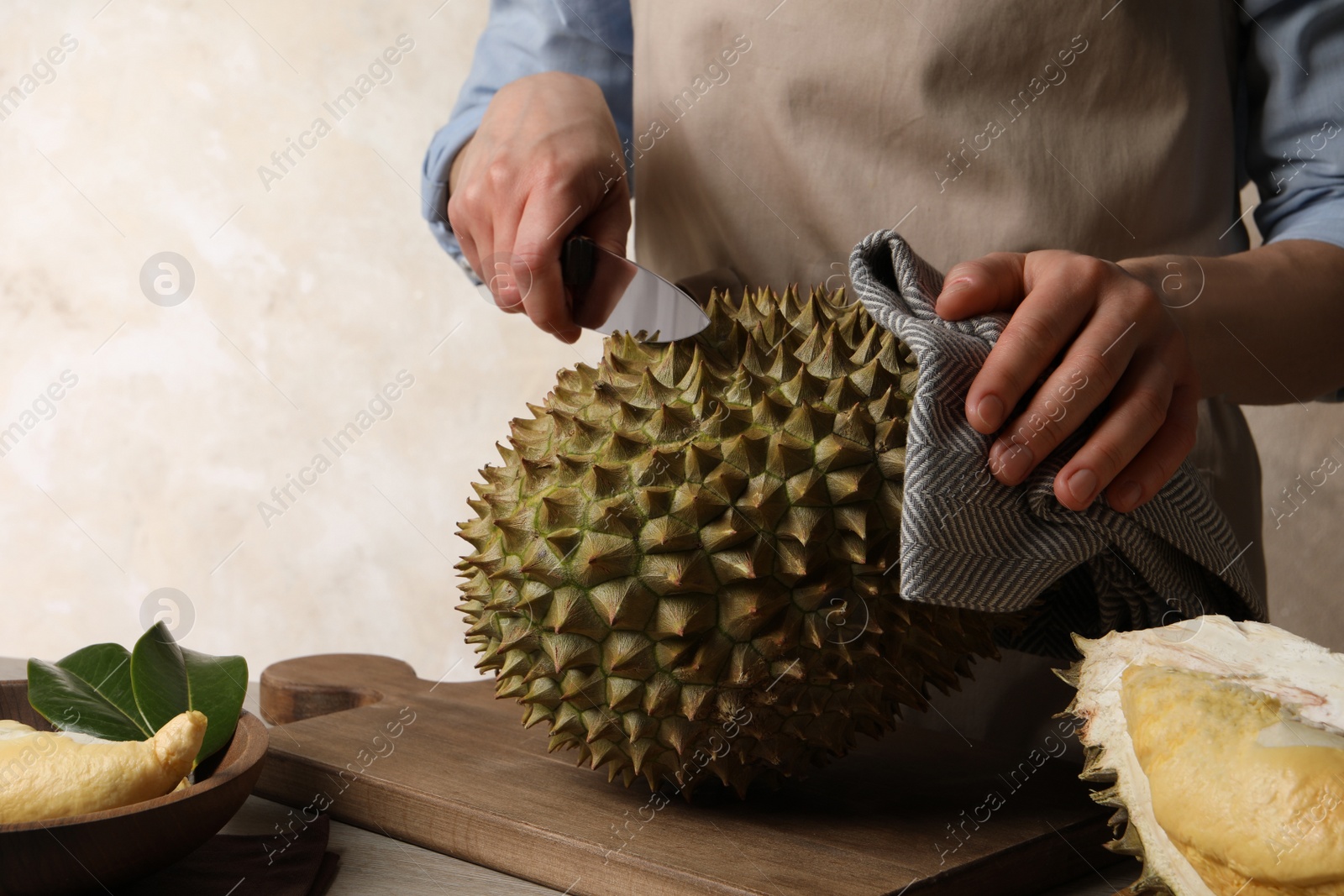 Photo of Woman cutting fresh ripe durian at table, closeup