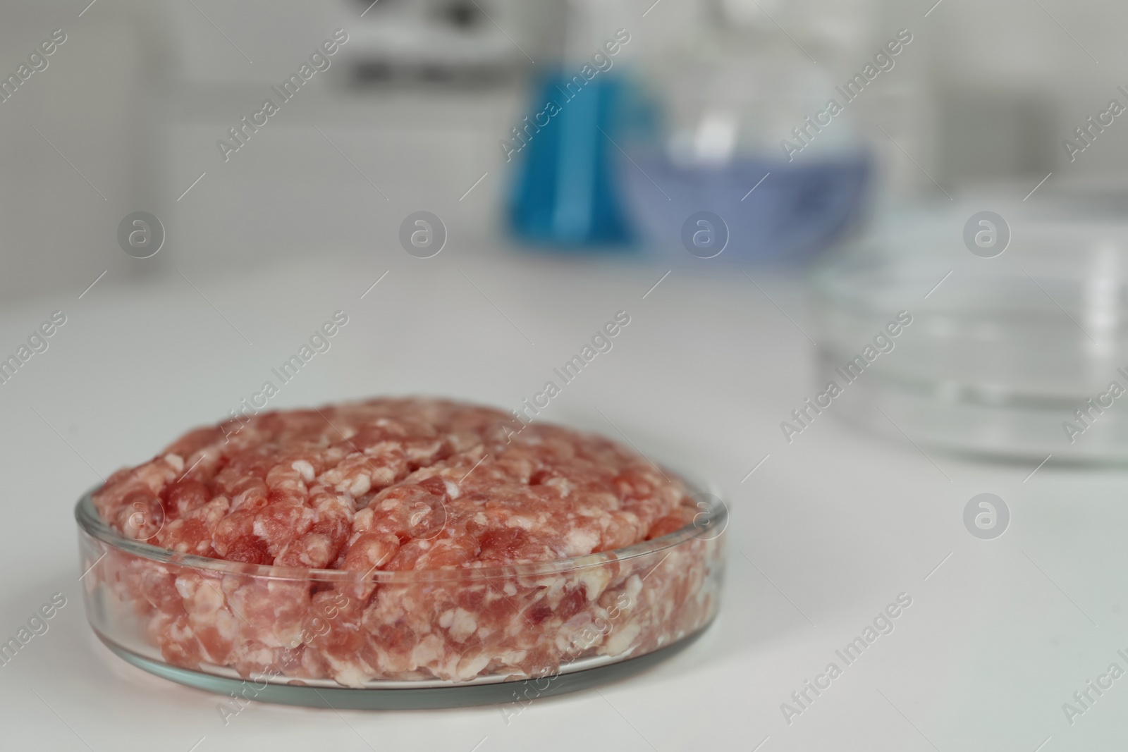 Photo of Petri dish with raw minced cultured meat on white table indoors, space for text