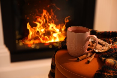 Cup of hot drink near fireplace at home. Space for text