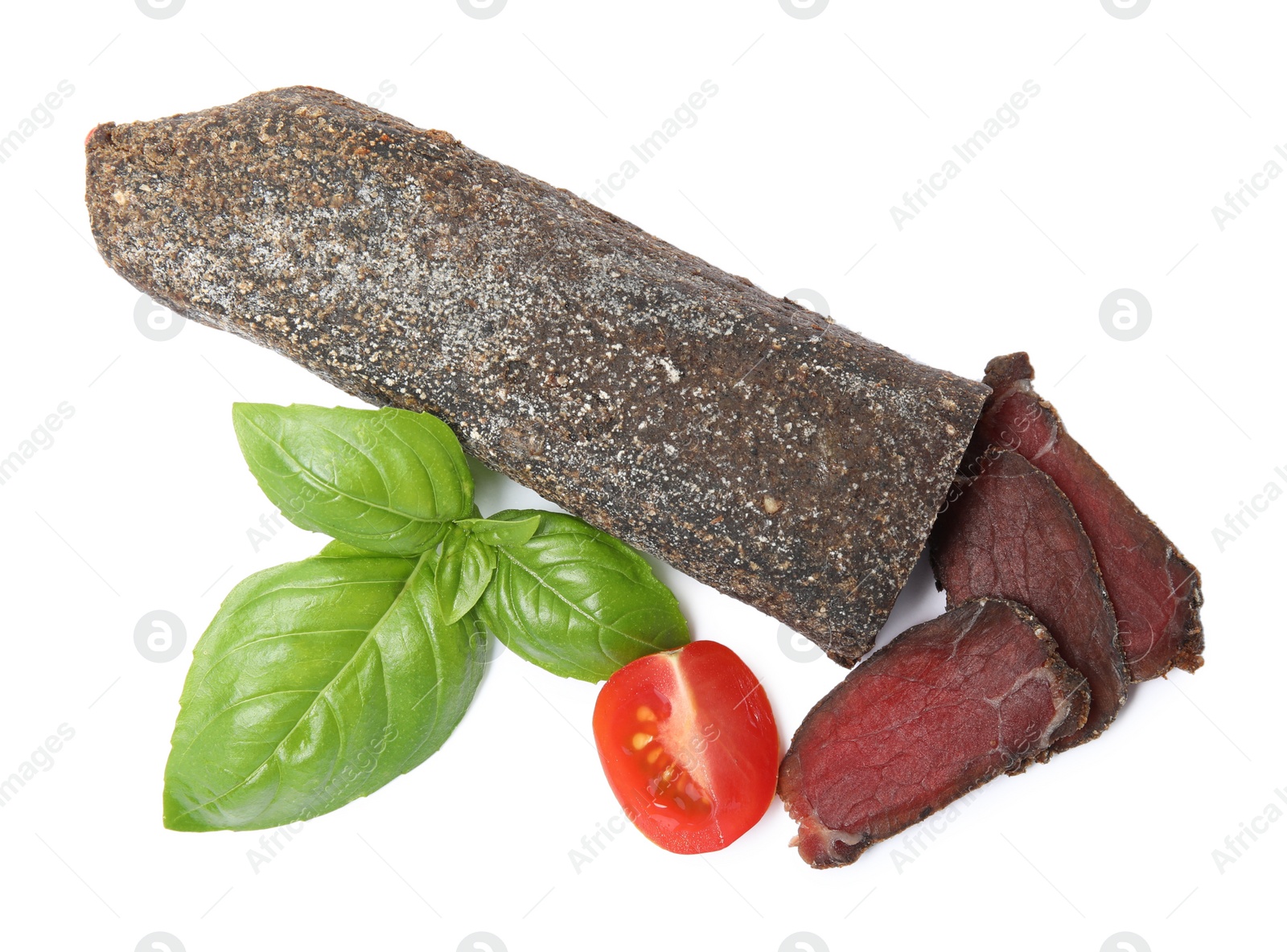 Photo of Delicious dry-cured beef basturma with basil and tomato on white background, top view