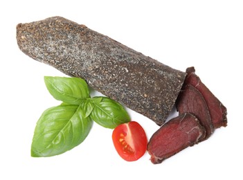 Delicious dry-cured beef basturma with basil and tomato on white background, top view