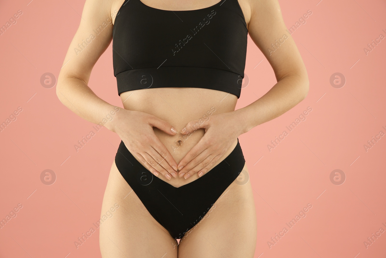 Photo of Gynecology. Woman in underwear making heart with her hands on pink background, closeup