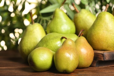 Fresh ripe pears on wooden table against blurred background