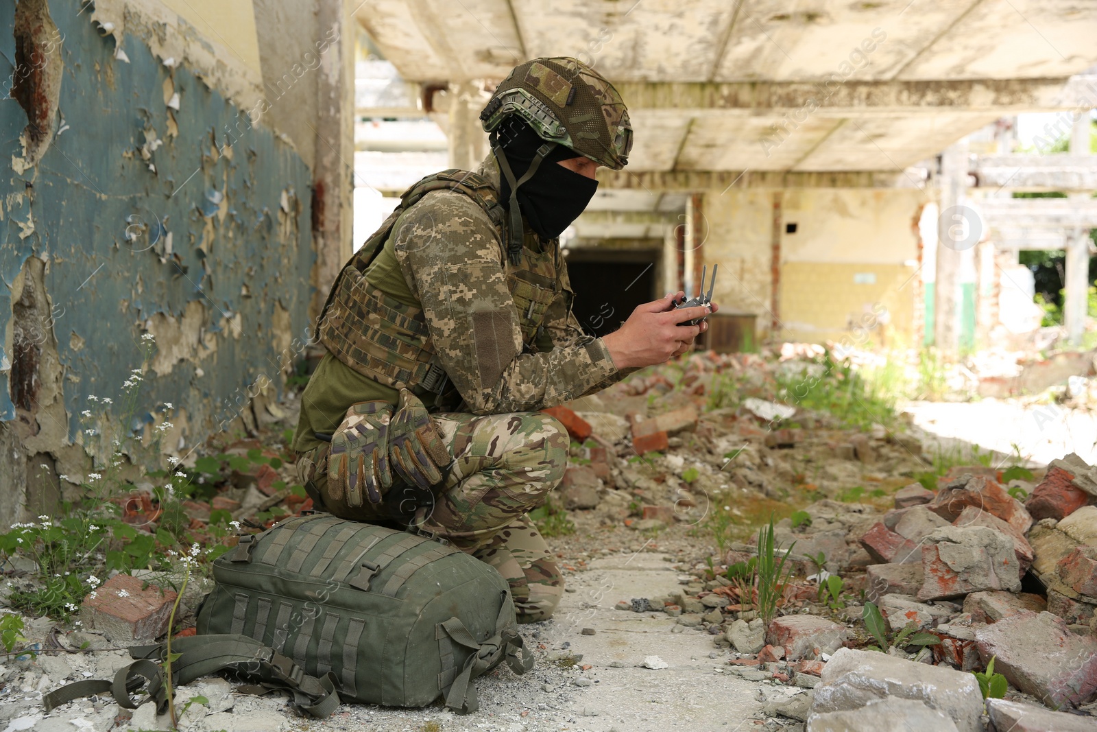 Photo of Military mission. Soldier in uniform with drone controller inside abandoned building