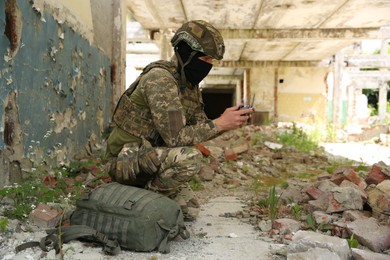 Military mission. Soldier in uniform with drone controller inside abandoned building