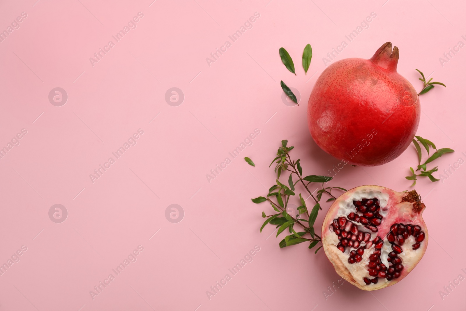 Photo of Flat lay composition with ripe pomegranates on pink background. Space for text