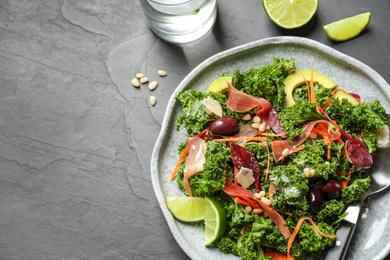 Tasty fresh kale salad on black table, flat lay. Space for text