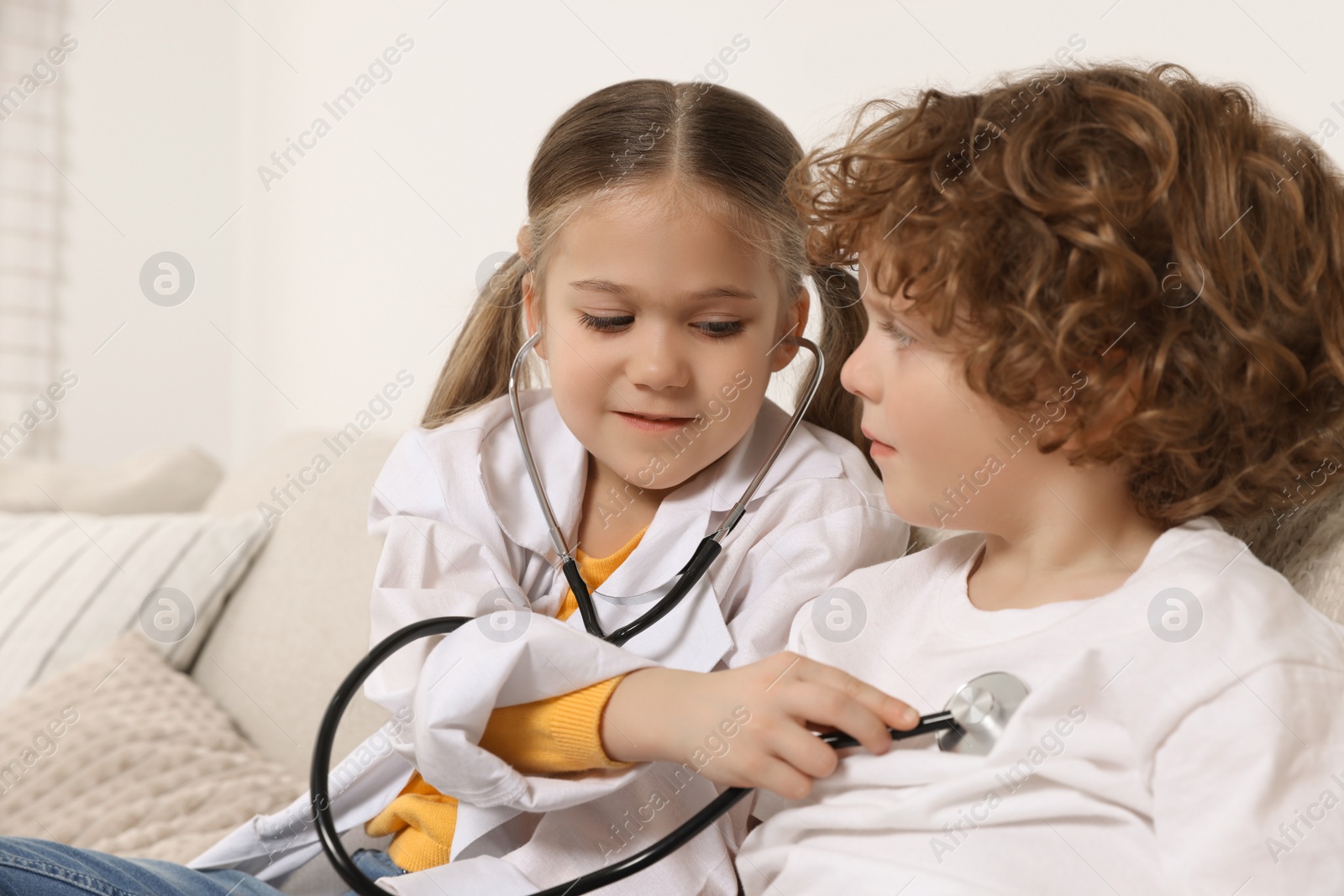 Photo of Little girl playing doctor with her friend at home