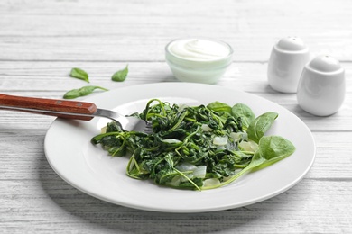 Photo of Tasty cooked spinach served on white wooden table. Healthy food