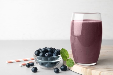 Fresh acai drink with berries on grey table against light background. Space for text