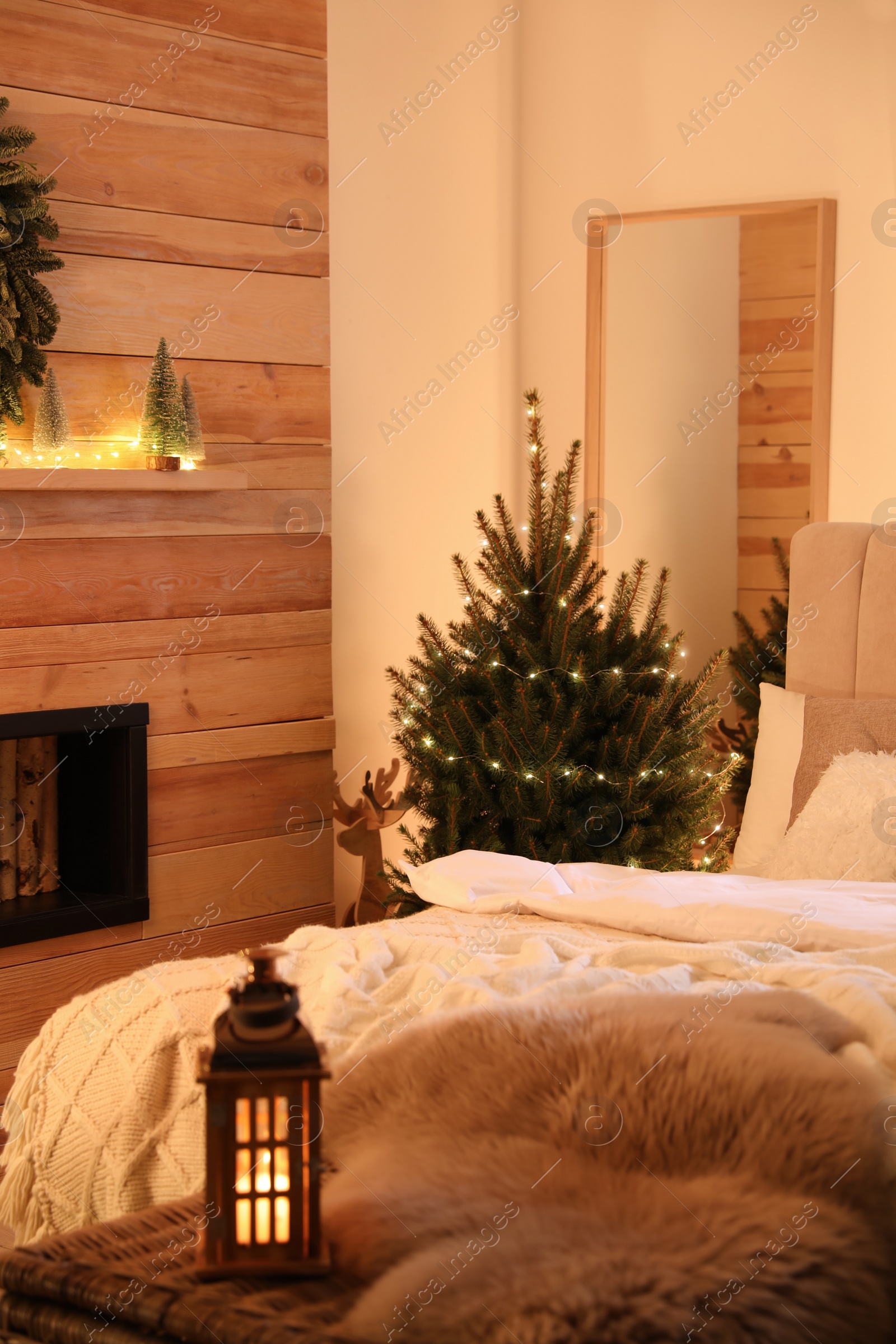 Photo of Beautiful decorated Christmas tree with fairy lights in bedroom interior