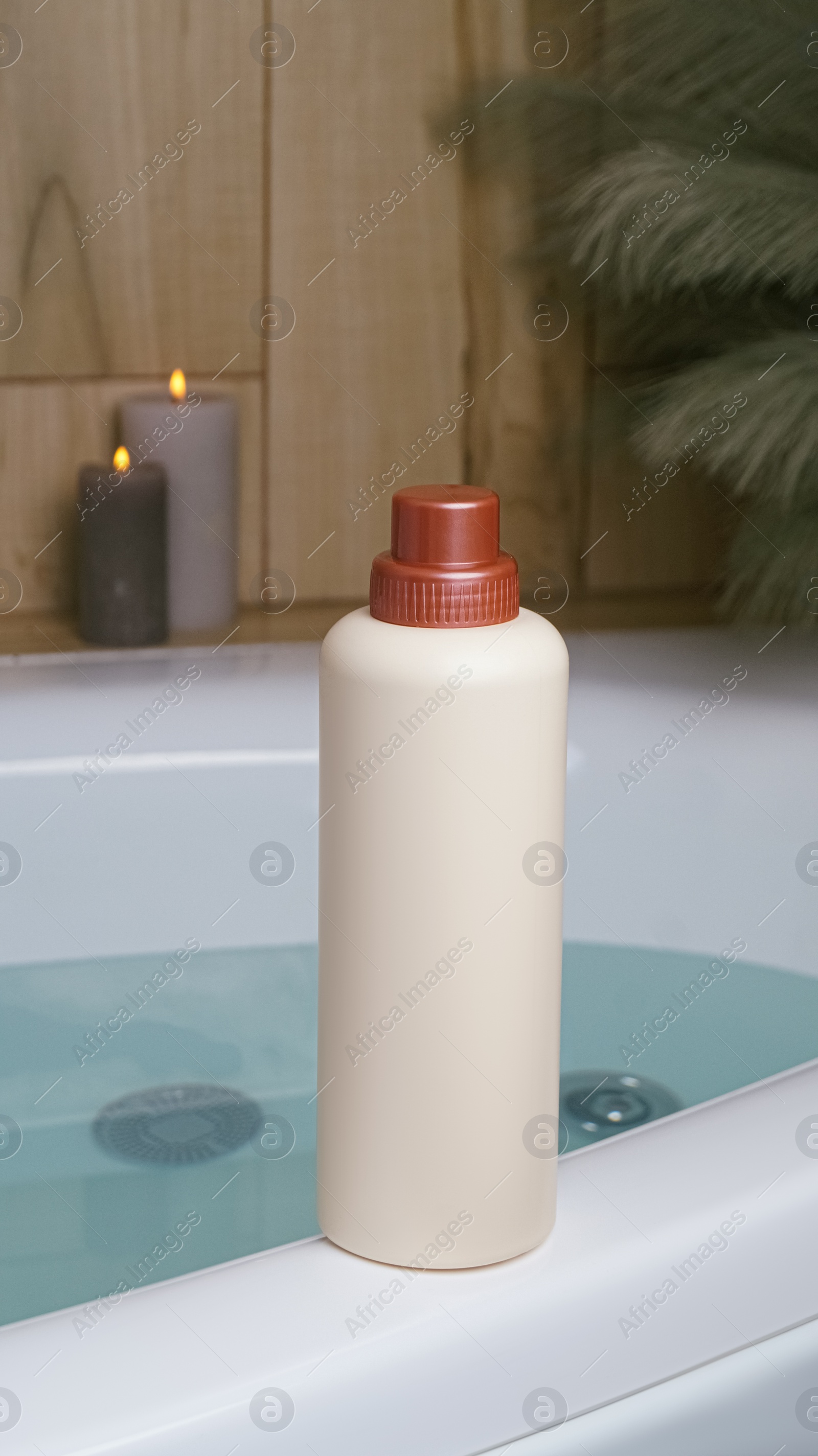 Beige bottle of bubble bath and candles on tub indoors Photo of Beige bottle of bubble bath and candles on tub indoors