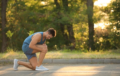 Young man in sportswear having knee problems in park