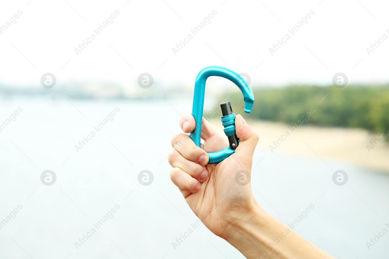 Photo of Woman holding metal carabiner outdoors, closeup view