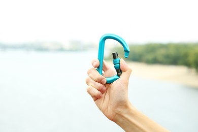 Woman holding metal carabiner outdoors, closeup view