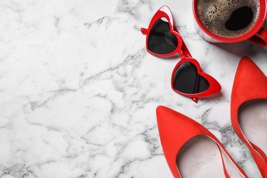 Cup of coffee, stylish women's shoes and heart shaped sunglasses on white marble background, flat lay. Space for text