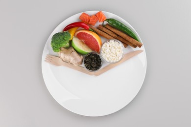 Photo of Metabolism. Plate with different food products and wooden cutlery on light grey background, top view