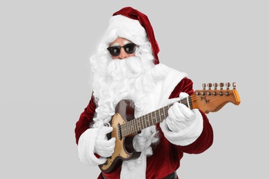 Photo of Santa Claus playing electric guitar on light grey background. Christmas music