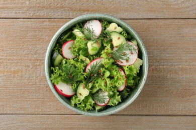 Delicious salad with radish, cucumber and lettuce on wooden table, top view