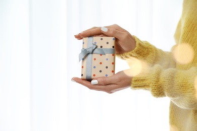 Woman in warm sweater holding Christmas gift on white background, closeup