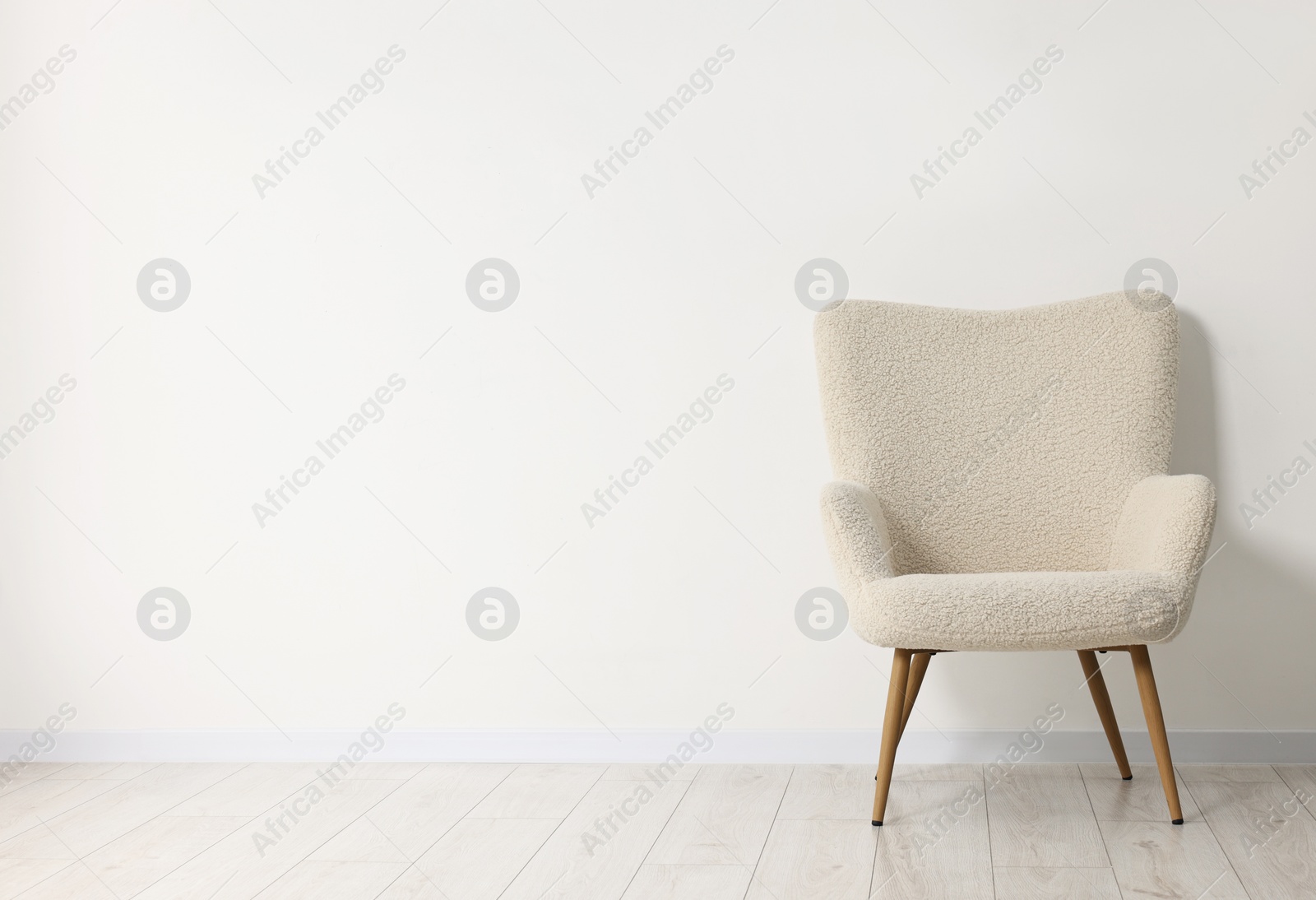 Photo of Comfortable armchair near white wall in room, space for text