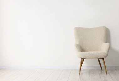 Photo of Comfortable armchair near white wall in room, space for text