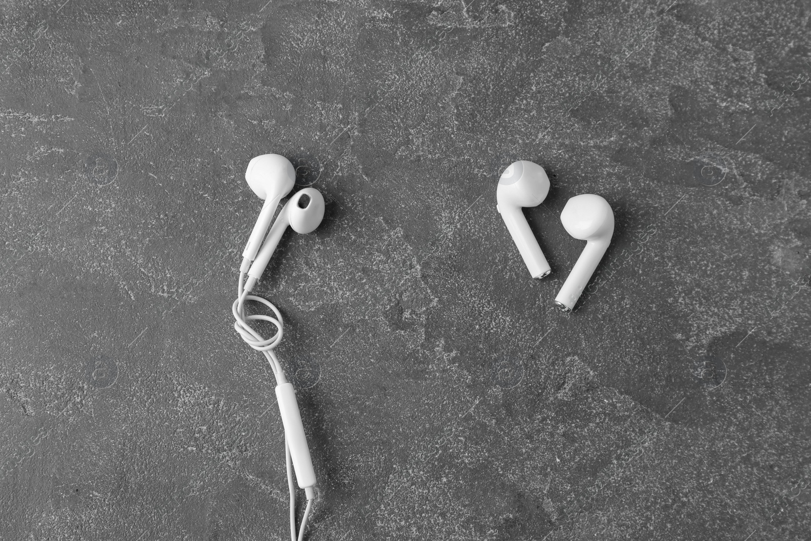 Photo of Flat lay composition with different earphones on grey stone background