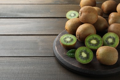 Photo of Fresh ripe kiwis on wooden table, space for text