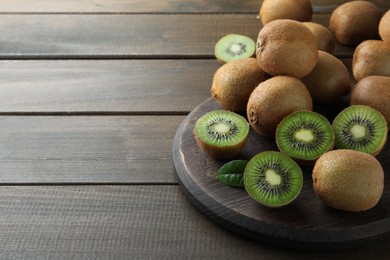 Fresh ripe kiwis on wooden table, space for text