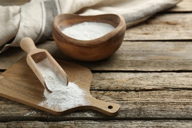 Baking powder in scoop and bowl on wooden table, closeup. Space for text