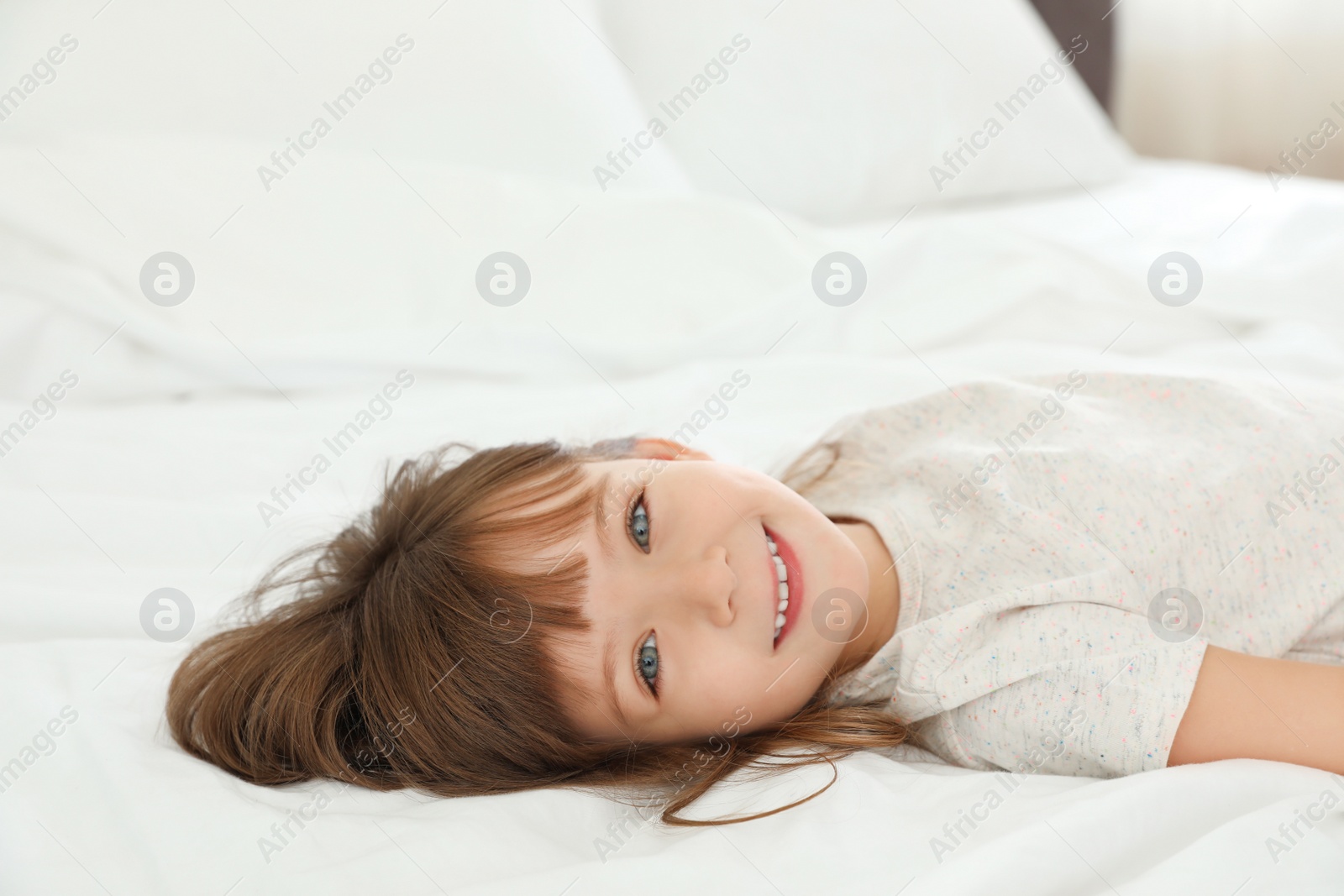 Photo of Portrait of cute little girl lying on bed at home