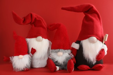 Photo of Many cute Christmas gnomes on red background