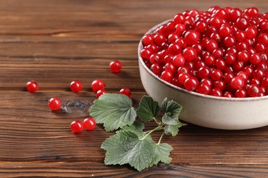 Ripe red currants and leaves on wooden table. Space for text