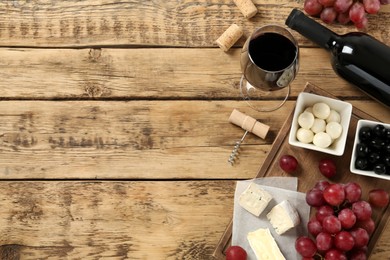 Photo of Flat lay composition with red wine and snacks on wooden table, space for text