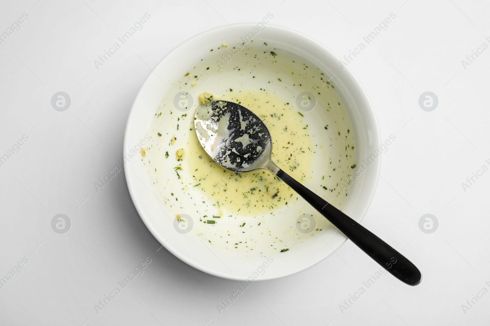 Photo of Dirty bowl with food leftovers and spoon on white background, top view