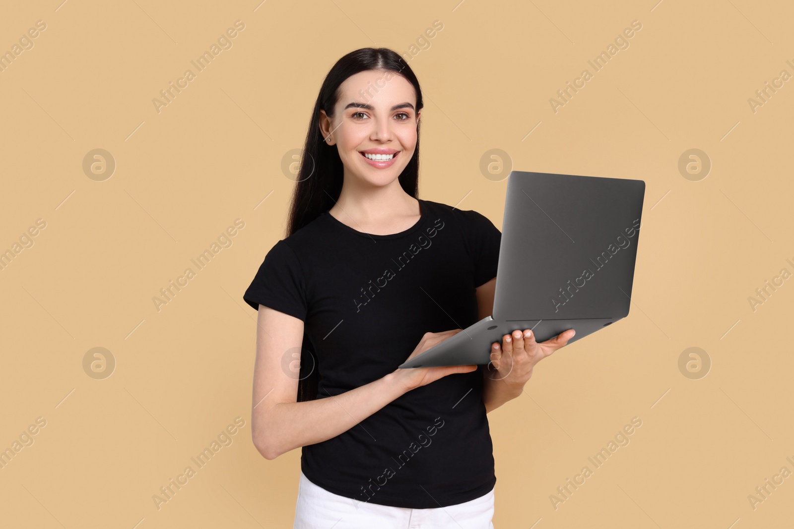 Photo of Happy woman with laptop on beige background