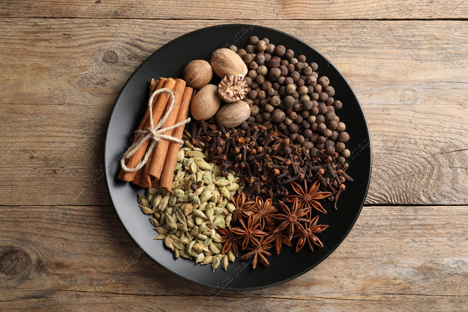 Photo of Different spices and nuts on wooden table, top view