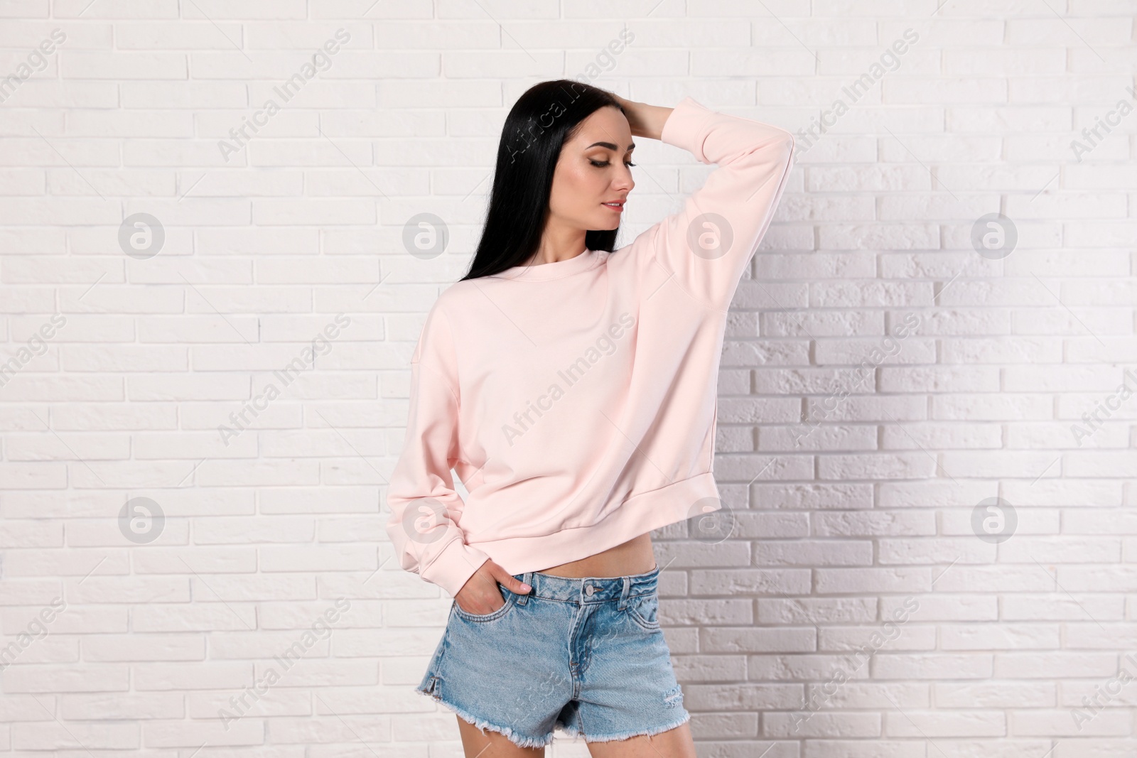 Photo of Portrait of young woman in sweater at brick wall. Mock up for design