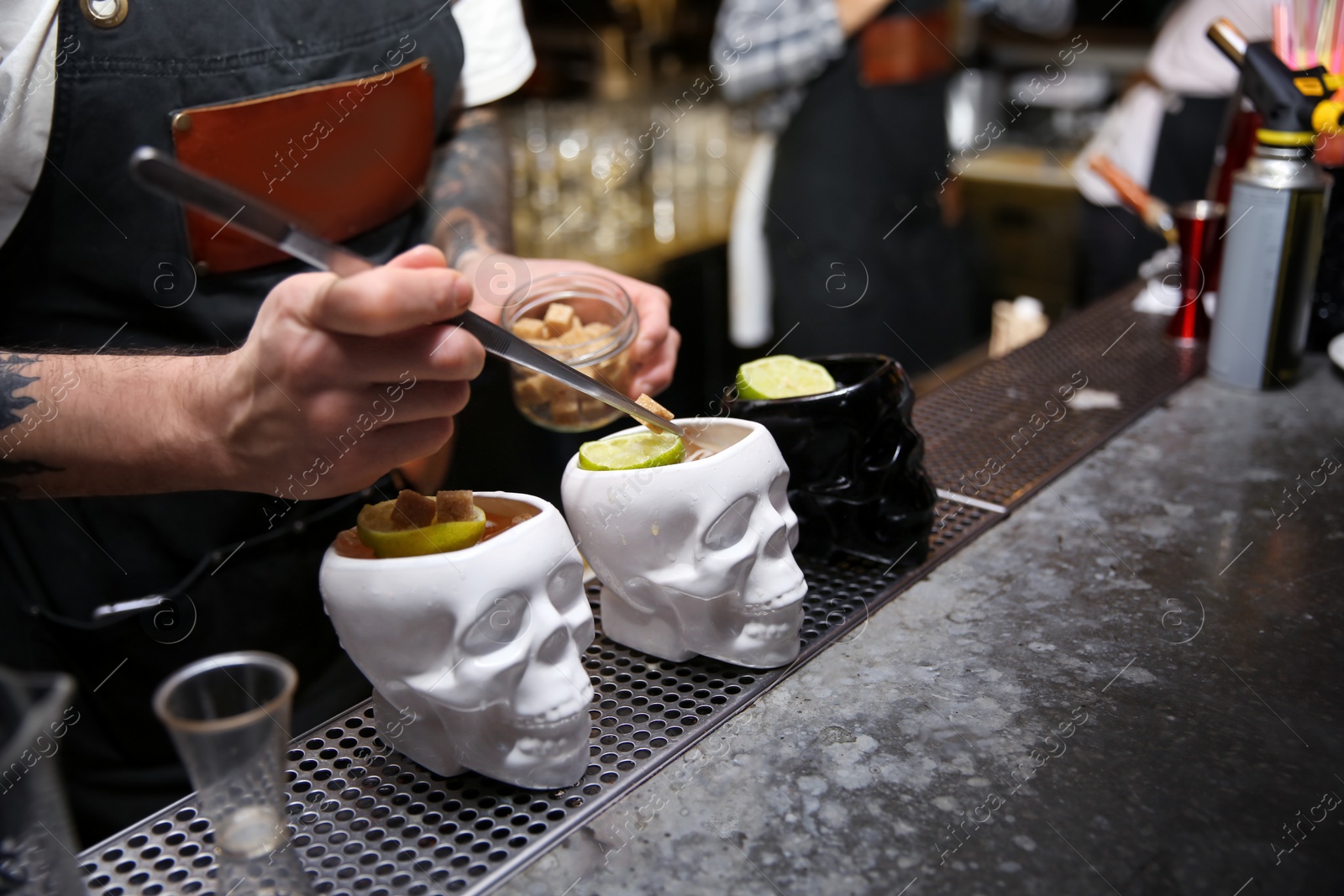 Photo of Bartender preparing tasty cocktail at counter in nightclub, closeup