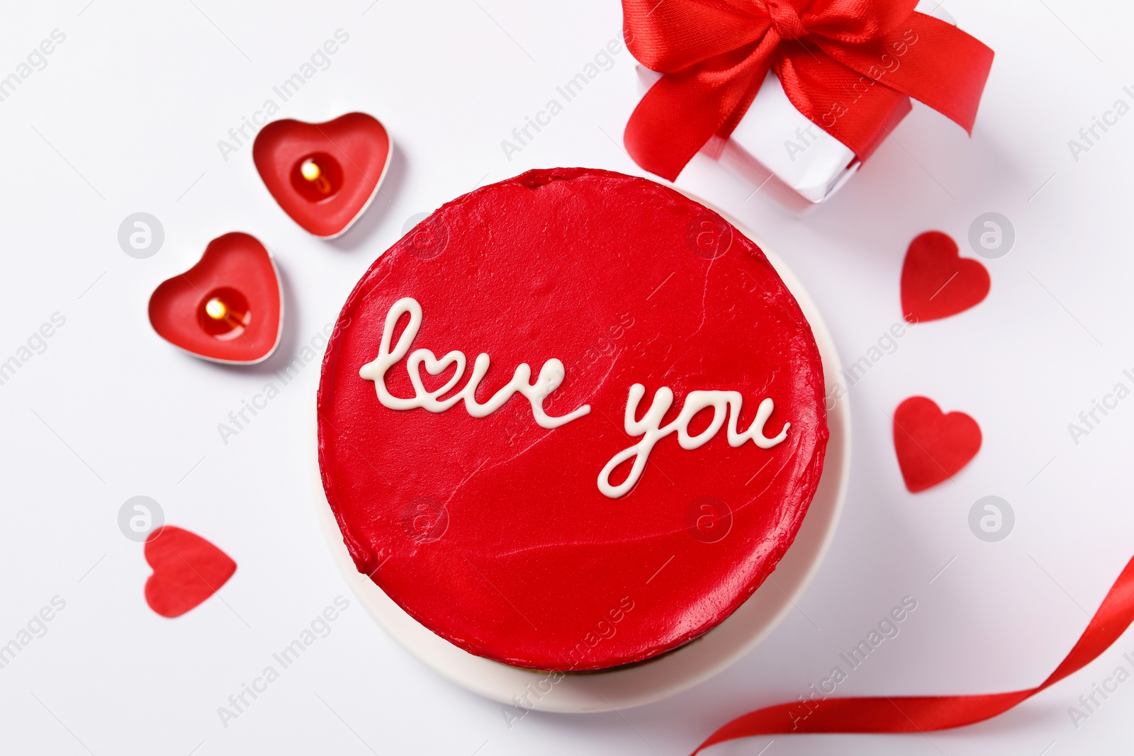 Photo of Bento cake with text Love You, candles, gift box and paper hearts on white table, flat lay. St. Valentine's day surprise