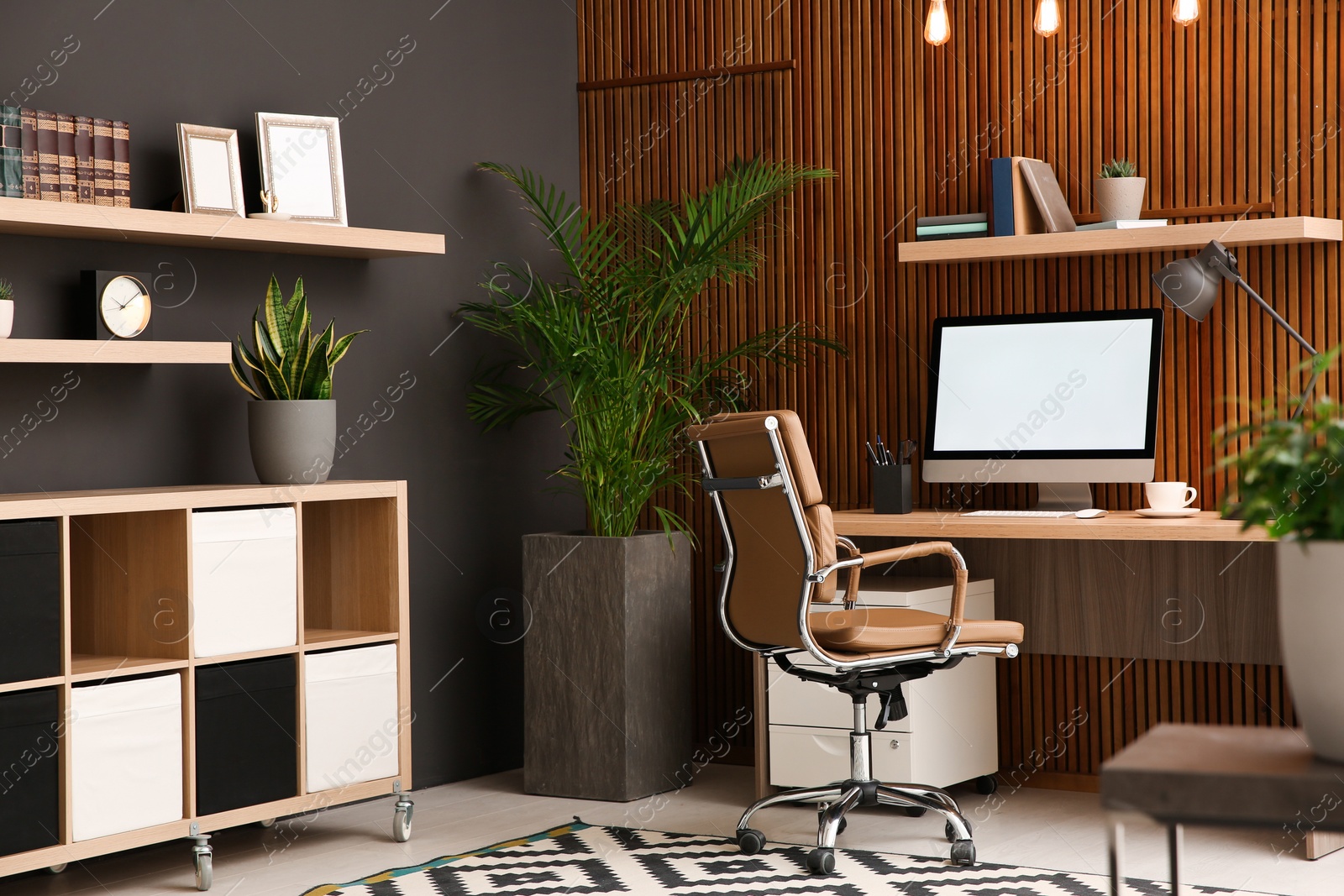 Photo of Comfortable workplace with computer near wooden wall in stylish room interior. Home office design